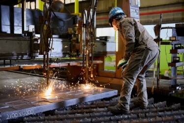 工場内で火花を散らしながら作業を行う男性作業員