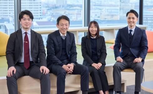 四人のビジネスパーソンがベンチに座っている様子