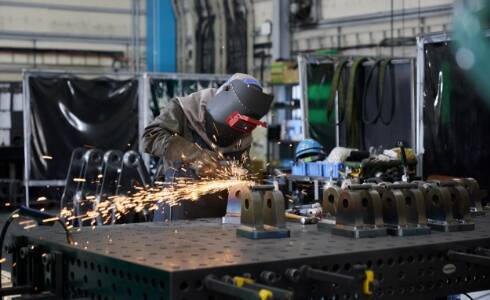 工場で金属を溶接している溶接工の姿。安全装備を着用し、集中して作業に取り組んでいる