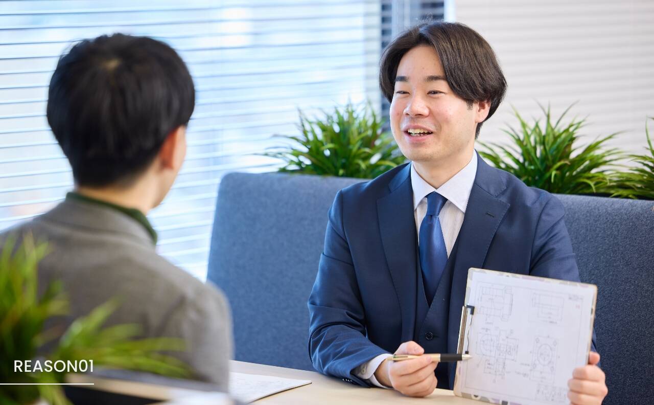 スーツを着た男性が商談相手の男性と話しているシーン