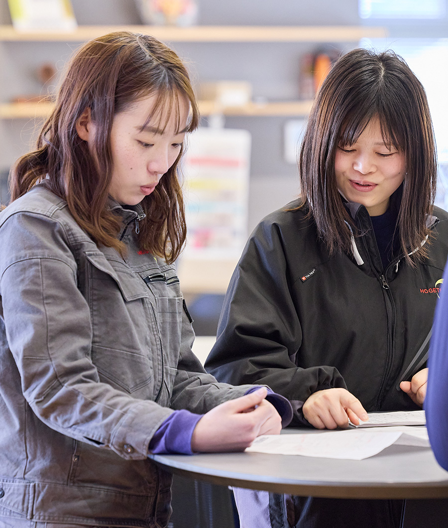 ヘルメットと作業着を着て工場内で作業をする女性。