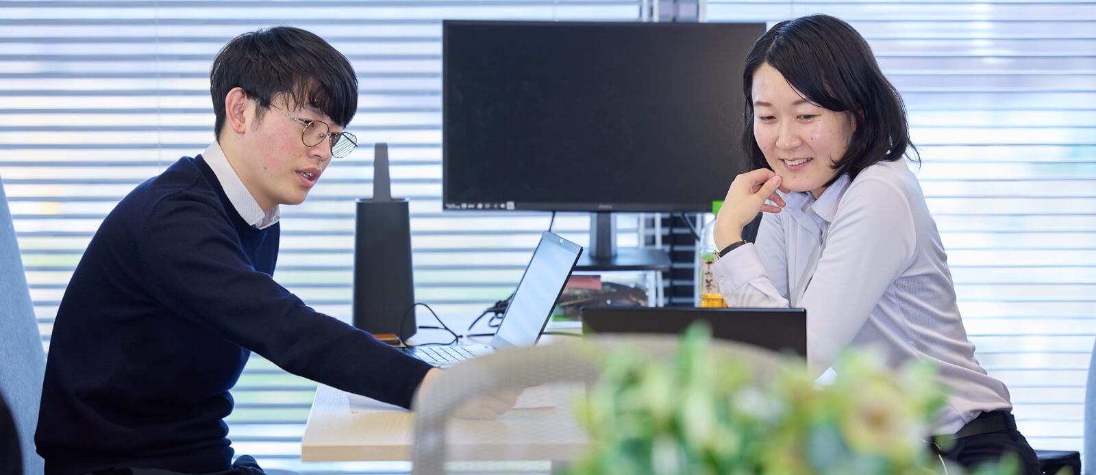 オフィスの打ち合わせスペースで男性と女性が話し合っている様子