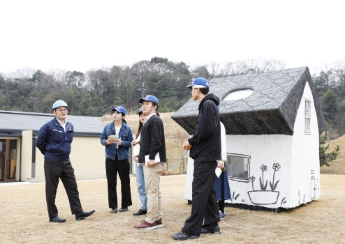 屋外で説明を聞く学生たち