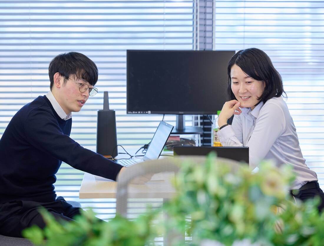 男性と女性が向かい合って座り、打ち合わせをする様子