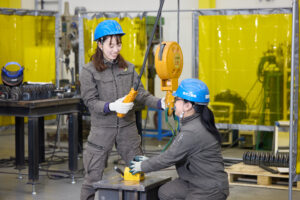 にこやかにクレーン作業を行う製造現場の女性2人